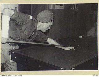 BOUGAINVILLE. 1945-04-26. PRIVATE H.M. KOHNING, 47 INFANTRY BATTALION, A PATIENT AT 2/3 CONVALESCENT DEPOT, PLAYS BILLIARDS TO PASS TIME WHILE HIS ARM, WHICH IS STILL IN PLASTER, HEALS