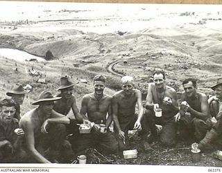 RAMU VALLEY, NEW GUINEA. 1943-12-19. TROOPS OF THE 2/2ND AUSTRALIAN PIONEER BATTALION ENJOYING THEIR LUNCH ON THE ROAD OVERLOOKING THE CAMP OF THE 2/6TH AUSTRALIAN FIELD COMPANY, ROYAL AUSTRALIAN ..