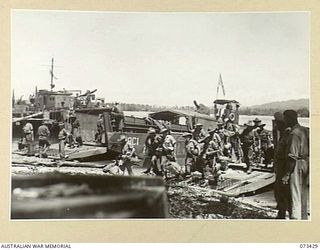 ALEXISHAFEN, NEW GUINEA. 1944-05-22. TROOPS OF THE 5TH DIVISION CARRIER COMPANY MOVING ASHORE FROM A LANDING BARGE AT NORTH ALEXISHAFEN