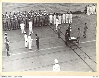 AT SEA OFF RABAUL, NEW BRITAIN. 1945-09-06. THE SURRENDER CEREMONY ON BOARD THE AIRCRAFT CARRIER HMS GLORY. A JAPANESE INTERPRETER SPEAKING TO VICE ADMIRAL J. KUSAKA, COMMANDER SOUTH EAST AREA ..