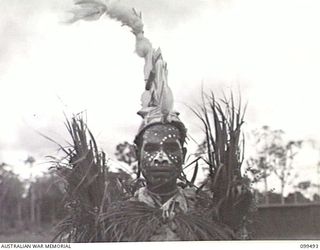 LAE, NEW GUINEA, 1945-12-25. A NATIVE DANCER WITH HIS ELABORATE HEADDRESS AND MAKE-UP ON AT THE NATIVE SING-SING HELD AT THE MALAHANG NATIVE LABOUR COMPOUND TO CELEBRATE CHRISTMAS. MANY ALLIED AND ..