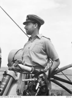 AT SEA OFF RABAUL, NEW BRITAIN. 1945-09-04. LIEUTENANT E. GERMAINE, ROYAL AUSTRALIAN NAVY, HOLDING THE SWORDS AND DIRKS OF THE JAPANESE ENVOYS DURING PRE- SURRENDER DISCUSSIONS ABOARD HMAS VENDETTA ..