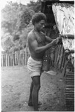 Man hanging shell money on the corner of a house