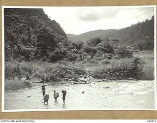 MUBO-SALAMAUA AREA, NEW GUINEA, 1943-07-21. NATIVE FOOD CARRIERS CROSSING THE BITOI RIVER
