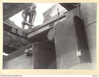 WEWAK AREA, NEW GUINEA. 1945-05-30. SAPPER H J INMAN, 2/8 FIELD COMPANY ROYAL AUSTRALIAN ENGINEERS, CHECKING A LOAD OF CORAL AFTER IT HAD BEEN TIPPED INTO THE TRUCK FOR THE NEW MAPRIK ROAD (BIG ..