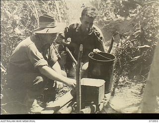 DUGUMUR BAY, NEW GUINEA. 1944-06-14. NX120971 STAFF SERGEANT B. SCANLAN (LEFT) AND NX175734 SERGEANT S. DOWSE, MEMBERS OF 4TH INFANTRY BATTALION, USING ABANDONED JAPANESE RIFLES AS FIRE BARS TO ..