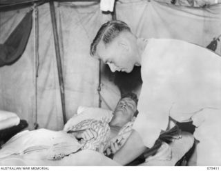 WUNUNG PLANTATION, JACQUINOT BAY, NEW BRITAIN. 1945-03-02. S112399 PRIVATE H.S. BUTCHER, MEDICAL ORDERLY (2), 105TH CASUALTY CLEARING STATION (2), GIVING A PENICILLIN INJECTION T102848. PRIVATE V. ..