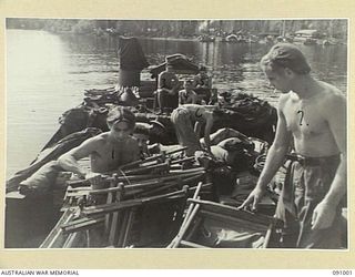 JACQUINOT BAY, NEW BRITAIN. 1945-04-17. MEN FROM 6 FIELD AMBULANCE ABOARD THE BARGE AB2027 DISCHARGING THEIR CARGO OF MEDICAL GEAR. THIS UNIT HAS BEEN RELIEVED FOR A HOMEWARD MOVE AFTER 23 MONTHS ..