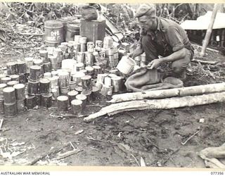 TOROKINA AREA, BOUGAINVILLE ISLAND. 1944-11-30. QX55999 STAFF SERGEANT L.W. PENTECOST, C COMPANY, 9TH INFANTRY BATTALION, SORTING TINNED RATIONS FOR DISTRIBUTION TO THE PLATOONS ON LITTLE GEORGE ..