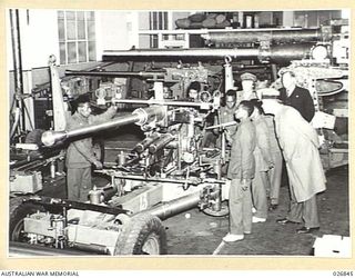 MARIBYRNONG, AUSTRALIA. 1942-10-12. SIX PAPUAN NATIVE SOLDIERS ON A TOUR OF INSPECTION OF THE MUNITION WORKS TAKE A KEEN INTEREST IN A NEARLY COMPLETED 40MM BOFORS ANTI-AIRCRAFT GUN