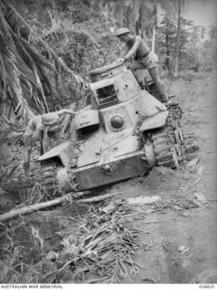A JAPANESE TYPE 95 HA-GO LIGHT TANK THAT WAS USED AGAINST THE AUSTRALIAN FORCES AT MILNE BAY. TWO MEN OF THE AIF ARE SEEN CLOSELY EXAMINING IT