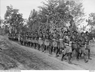 BOUGAINVILLE. 1945-05-23. PERSONNEL OF A COMPANY, PAPUAN INFANTRY BATTALION, MARCHING FROM FREDDIE BEACH, SORAKEN, TO THE PARADE GROUND, FOR AN INSPECTION BY BRIGADIER J.R. STEVENSON, COMMANDER 11 ..