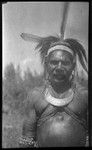 Man with feather head piece, shell armbands, and a crescent shell valuable necklace called kina, on Goaribari Island