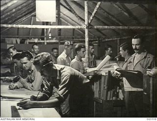 AITAPE, NORTH EAST NEW GUINEA. C. 1944-06. AT NO. 13 SURVEY AND DESIGN UNIT RAAF RAAF SURVEYORS AND DRAUGHTSMEN IN THEIR DRAWING OFFICE, WORK BY THE LIGHT OF CAPTURED GLOBES AND POWER PLANT