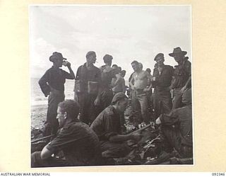 GAZELLE PENINSULA, NEW BRITAIN, 1945-05-15. TROOPS OF A COMPANY, 37/52 BATTALION, TAKING A PAUSE AFTER THEIR ARRIVAL AT THE BEACH ON THE NORTH COAST OF NEW BRITAIN AT THE END OF THEIR TREK FROM ..