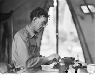 AITAPE, NEW GUINEA. 1944-11-29. COLONEL J H RASMUSSEN, DIRECTOR GENERAL OF PUBLIC RELATIONS, AT WORK IN A TENT HQ 6 DIVISION AREA