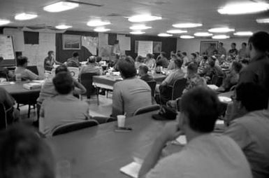 Navy and Marine officers receive an operational status briefing in the wardroom aboard the amphibious assault ship USS SAIPAN (LHA 2). The SAIPAN is on station off the coast of Liberia for Operation Sharp Edge