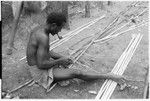 Man shaves split bamboo for use in wall construction