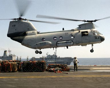 An HH-46D Sea Knight from Helicopter Combat Support Squadron 6 (HC-6) prepares to pick up a pallet from the flight deck of the nuclear-powered aircraft carrier USS THEODORE ROOSEVELT (CVN-71) during an underway replenishment operation. The fleet oiler USNS KANAWHA (T-AO-196) and the amphibious assault ship USS SAIPAN (LHA-2) are in the background. The ROOSEVELT Battle Group is assisting in enforcement of the no-fly zone over Bosnia-Herzegovina during Operation Deny Flight
