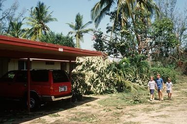 Children walk past branches strewn on the ground of the housing area at the Pacific Missile Range Facility, Kauai, in the aftermath of Hurricane Iniki