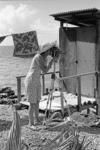 Woman filming. Clothes line attached to sea latrine in background.