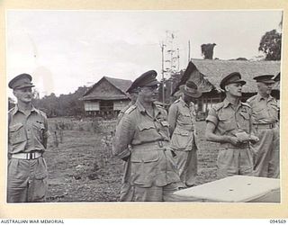 TOROKINA, BOUGAINVILLE, 1945-08-04. AN AUSTRALIAN NEW GUINEA ADMINISTRATIVE UNIT OFFICIAL TRANSLATING THE SPEECH MADE BY LIEUTENANT-GENERAL S.G. SAVIGE, GENERAL OFFICER COMMANDING 2 CORPS (2), AT ..