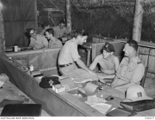 GOODENOUGH ISLAND, PAPUA. C. 1943-11. RAAF PUBLIC RELATIONS OFFICERS INTERVIEWING MEMBERS OF NO. 75 (KITTYHAWK) SQUADRON RAAF AT VIVIGANI. IN THE FOREGROUND IS FLIGHT LIEUTENANT J. WATERS WITH ..