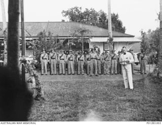 SALAMAUA, NEW GUINEA, 1940-04-25. THE SALAMAUA PLATOON OF THE NEW GUINEA VOLUNTEER RIFLES (NGVR), ON PARADE IN FRONT OF THE DISTRICT OFFICE, LISTEN TO AN ADDRESS BY A COLONIAL OFFICIAL (POSSIBLY ..