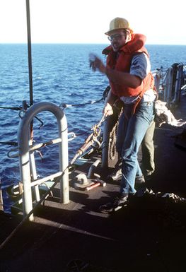 Boatswain's Mate 2nd Class (BM2) Leo Grudzinski, aboard the amphibious assault ship USS SAIPAN (LHA-2), gives a hand signal during preparations for underway refueling. The SAIPAN is taking part in Exercise Ocean Venture '81