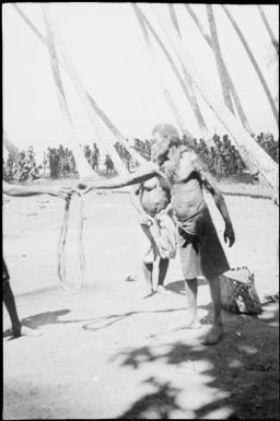 Man passing a coil of rope with many onlookers, Papua, ca. 1923 / Sarah Chinnery
