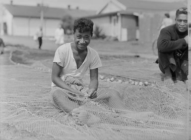 [Portrait of a young Polynesian man working on a fishing net]