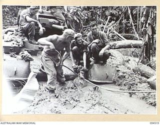 TOROKINA, BOUGAINVILLE, 1945-08-02. TROOPS ATTACHING A BLOCK AND TACKLE TO A BOGGED MATILDA TANK AT THE COMMENCEMENT OF RECOVERY OPERATIONS. THE MACHINE IS TAKING PART IN TRIALS OF THE M24 GENERAL ..