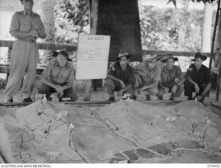 SIAR, NEW GUINEA. 1944-08-19. PERSONNEL OF THE INTELLIGENCE SECTION, HEADQUARTERS, 7TH INFANTRY BRIGADE, DISPLAYING A SAND MODEL WHICH THEY MADE OF THE SAIDOR AREA. IDENTIFIED PERSONNEL ARE LEFT TO ..