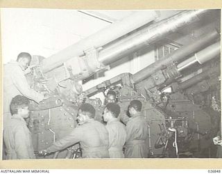 MARIBYRNONG, AUSTRALIA. 1942-10-12. SIX NATIVE SOLDIERS FROM NEW GUINEA WHO WERE SHOWN OVER THE MUNITION WORKS AT MARIBYRNONG ARE SEEN HERE EXAMINING THE MOUNTING OF A BIG GUN