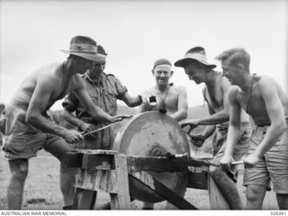 PAPUA. 1942-08-18. GETTING READY FOR THE JAPS. VETERANS OF THE SYRIAN CAMPAIGN, MEN OF THE 2/14TH AUSTRALIAN INFANTRY BATTALION SHARPEN THEIR BAYONETS ON A GRINDSTONE THEY HAD DISCOVERED IN A ..