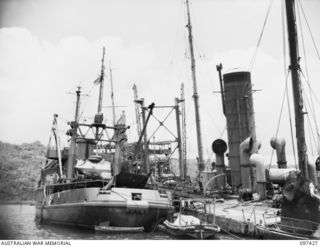 RABAUL, NEW BRITAIN. 1945-09-30. THE SALVAGE SHIP, CAMBRIAN SALVOR, OPERATED BY COMMONWEALTH SALVAGE BOARD, WORKING ALONGSIDE THE JAPANESE TANKER NO. 5301 WHICH WAS DAMAGED IN SIMPSON HARBOUR ..