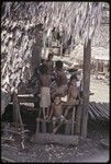 Woman and smiling children gathered on a house veranda, Tukwaukwa village, Kiriwina