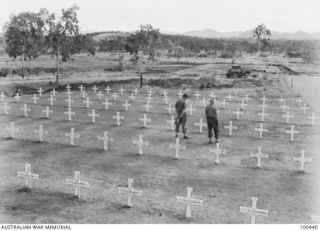 Berry airstrip, New Guinea. 1944-05-09. Two soldiers stand in a section of the Bomana War Cemetery, conducted by 1 Graves Registration Unit. Australians and members of the Papuan Infantry Battalion ..