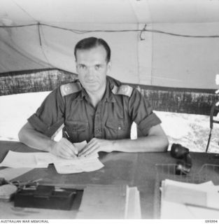 CAPE WOM, WEWAK AREA, NEW GUINEA. 1945-09-01. MAJOR G.H. MARTIN, DEPUTY ASSISTANT DIRECTOR OF ORDNANCE SERVICE, HEADQUARTERS 6 DIVISION, AT HIS DESK