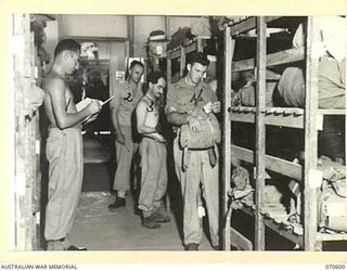 ON ADMISSION TO THE 2/1ST AUSTRALIAN GENERAL HOSPITAL, PATIENTS DEPOSIT CLOTHES AND EQUIPMENT IN THE PACK STORE, MEMBERS OF THE STAFF ARE PICTURED CHECKING THE ITEMS. IDENTIFIED PERSONNEL ARE:- ..