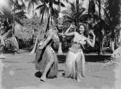 [Pacific Island man and woman in grass skirts]