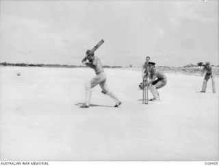 VIVIGANI, GOODENOUGH ISLAND, PAPUA. 1943-12-26. AIRMEN OF NO. 30 (BEAUFIGHTER) SQUADRON RAAF, PLAYING A GAME OF CRICKET AT THE END OF LANDING STRIP. FLIGHT SERGEANT J. SMITH OF ADELAIDE, SA, IS ..