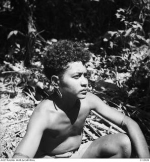 1942-12-23. PAPUA. SOPUTA. MAIN DRESSING STATION NEAR SOPUTA. THIS NATIVE BOY ASSISTS AT THE DRESSING STATION. HIS MOST PRIZED POSSESSION IS THE LARGE SIZED SAFETY PIN WHICH HE WEARS IN HIS EAR. ..