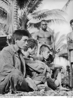 SINGORKAI, NEW GUINEA. 1944-03-19. FOUR JAPANESE PRISONERS GUARDED BY A NATIVE OF THE PAPUAN INFANTRY BATTALION