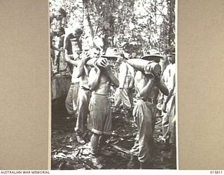 1943-09-25. NEW GUINEA. FALL OF LAE. ARTILLERY PLAYED A BIG PART IN THE FALL OF LAE. DURING THE ADVANCE ARTILLERY WAS HAULED THROUGH JUNGLES AND OVER STREAMS. AMMUNITION BEING CARRIED UP TO THE GUN ..