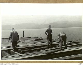 LAE, NEW GUINEA, 1943-11-05. ENGINEERS OF THE 1052ND ENGINEERS PORT CONSTRUCTION AND REPAIR GROUP, UNITED STATES ARMY, WORKING ON THE CONSTRUCTION OF THE FIRST LIBERTY DOCK. CENTRE IS ASN-33480320 ..