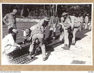 DREGER HARBOUR, NEW GUINEA. 1943-12-03. ENGINEERS OF THE 870TH UNITED STATES AVIATION ENGINEER BATTALION LAYING STEEL SECTIONS FOR A NEW LANDING STRIP WHICH WILL BE 6000 FEET LONG AND 110 FEET WIDE ..