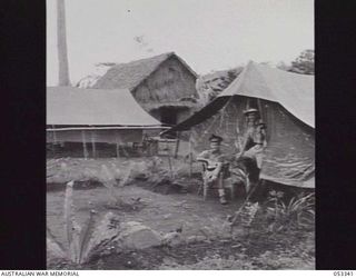 SOGERI VALLEY, NEW GUINEA. 1943-06-25. QX53208 LIEUTENANT F. A. N. STENLAKE (SITTING) AND QX39260 CAPTAIN B. HOOPER, OUTSIDE THEIR TENT AT 11TH AUSTRALIAN FIELD AMBULANCE HEADQUARTERS
