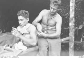 SHAGGY RIDGE, NEW GUINEA. 1943-12-27. A WOUNDED SOLDIER OF THE 2/16TH AUSTRALIAN INFANTRY BATTALION, 21ST AUSTRALIAN INFANTRY BRIGADE BEING BANDAGED BY A REGIMENTAL AID POST ORDERLY DURING THE ..