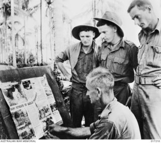 New Guinea. 30 May 1944. Corporal J. Kinnell of Bunbury of WA pins a Newsmap to a notice board. Watching are Private (Pte) J. Davis of Nunnawil, Vic, Pte R. Montgomery of Mungindi, NSW and Pte D. ..